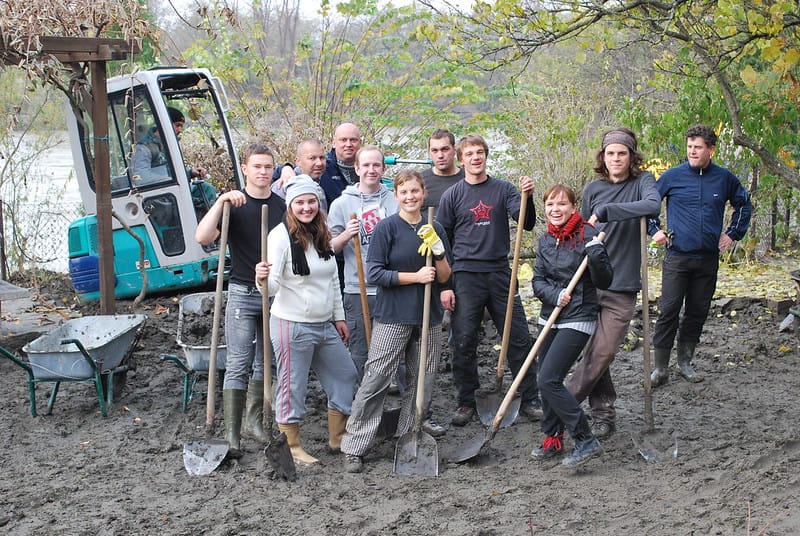 Volunteer group photo holding shovels in the mud.